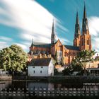 Text unten: "Kathedrale von Uppsala". Im Hintergrund große Kathedrale mit spitzen Türmen, Wasser und Bäume im Vordergrund.
