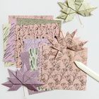 Verschiedene Bögen Origami-Papier, teils gefaltet zu Blättern, mit floralen und geometrischen Mustern.