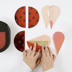 Mehrere bunte, geometrische Formen und Hände, die sie anordnen. Kreise mit Punkten und herzähnliche Formen.