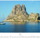 "Es Vedra", "12". Segelboot vor markanter Felseninsel im blauen Meer unter klarem Himmel.