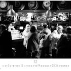 Zahlen von 1 bis 31, groß 12, darunter "CASARES EDITION". Menschen stehen in einer Bar mit Regalen voller Flaschen.