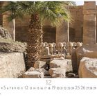 Text: Karnak, 12. Kalender mit antiken Ruinen, Säulen, Statuen und einer Palme im Vordergrund.