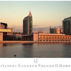 "Torres Vasco da Gama" steht links. Moderne Gebäude im Sonnenuntergang, spiegeln sich im Wasser. Unten Kalender mit Dezember.