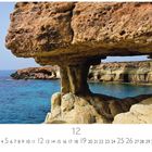Agia Napa, Stone Arch. Kalenderseite 12. Küstenlandschaft mit natürlichem Steinbogen über türkisblauem Wasser.