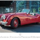 Löwengasse Schild, roter Oldtimer mit offenem Verdeck, elegantes Design. Nummernschild: "HG-HF 25H".