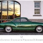 "VW Karmann Ghia", Kalenderblätter mit Zahlen. Grünes klassisches Auto vor einem Gebäude mit großer Glasscheibe bei Sonnenuntergang.