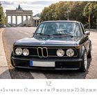 BMW 323i. Ein schwarzes Auto steht vor dem Brandenburger Tor auf einer leeren Straße.
