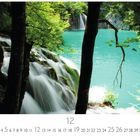 Kroatien, Plitvizer Seen. 
Dezember 12. 
Blick auf türkisfarbenen See durch dichte Bäume, mit Wasserfall.