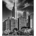 "Empire State Building" steht unter einem hohen Wolkenkratzer. Darunter ein Kalender mit Dezember-Daten und Bäumen im Vordergrund.