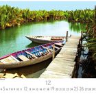 Traditionelle Ruderboote am Mekong. Kalenderseite für den Monat 12 mit hölzernem Steg und üppigem Grün entlang des Flusses.