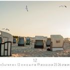 "Am Strand von Prerow." Eine Reihe von Strandkörben auf sandigem Boden bei Sonnenuntergang, Möwen fliegen darüber.