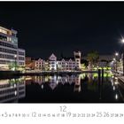 "Dortmund Phoenixsee" steht unter einem nächtlichen Stadtbild mit beleuchteten Gebäuden und ihrer Spiegelung im Wasser.