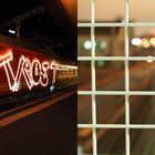 Links Schriftzug "Trost" auf schnell fahrendem Zug; rechts Gitter im Vordergrund, dahinter verschwommene Lichter.