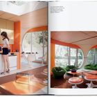 „The historical photos depict the house...“ Retro-Raum mit runden Fenstern, orangenen Wänden und grünen Sesseln.