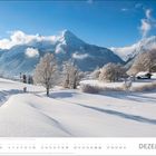 DEZEMBER, eine verschneite Landschaft mit Bergen, Bäumen und einer Hütte unter einem blauen Himmel.