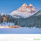 Kalenderblatt für Dezember 2021, verschneite Landschaft mit Bergen und einem beleuchteten Gebäude am Waldrand.