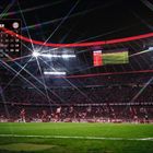 DEZEMBER Kalender mit Bayern-Logo. Stadion bei Nacht, Fans mit Fahnen, Spielfeld, bunte Lichtstrahlen, Anzeigetafel.