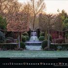 Dezember 2023. Ein gepflegter Garten mit einem zentralen Wasserbrunnen, umgeben von Bäumen und Sträuchern im Winter.