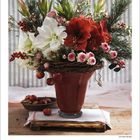 Dezember 2027. Ein Blumenarrangement in Rot und Weiß in einer Vase mit reichlich grünen Zweigen. Beige Hintergrund.