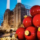 Weihnachtsdekoration an der Battersea Power Station. Große rote Kugeln, beleuchtete Bäume, ikonische Türme. Dez. Kalender.
