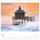 Monatsname "12", darunter ein Kalender mit Daten. Ein Steg mit Holzhütte ragt in ein winterliches Gewässer, Sonnenuntergang.