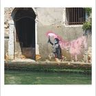 Kalender mit Graffiti: Kind mit pinker Rauchfackel auf verwitterter Wand. Tür und Fenster daneben, Wasser im Vordergrund.