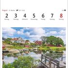 August-Kalenderwoche zeigt Figeholm in Småland. Charmante Landschaft mit Häuschen, Wasser und Booten bei blauem Himmel.