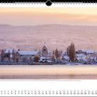 Mitte Januar 2021: Viel Schnee am See. Kalenderblatt Dezember 2021. Verschneite Landschaft mit Kirche und Gebäuden vor bewaldeten Hügeln.