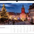 Dezemberkalender; Weihnachtsmarkt mit geschmücktem Baum, Lichterketten und historischem Gebäude bei Abenddämmerung.