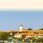Text "LAND UND LEUTE" oben. Malerische Küstenstadt mit roten Dächern, Kirche und Hafen voller Boote, strahlender Himmel.
