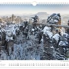 Kalenderseite Dezember, Basteibrücke von Schnee bedeckt. Winterlandschaft mit schneebedeckten Felsen und Bäumen.