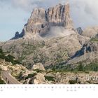 Text: "Dezember", darunter ein Kalender mit Adventstagen. 
Berglandschaft mit kurviger Straße und Fahrradfahrern. QUALDICH Logo.