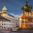 Texte: "KAIS. KÖN. PRIV.", Gebäude mit Kuppel im Hintergrund, Reiterstatue im Vordergrund, Menschen auf einem Platz.