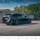 Kalender für November, Auto: BMW M5 Touring (G99), schwarz, vor einer Betonwand, umgeben von Bäumen.