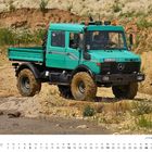 Text: "EN-U 1250 H", "DEZEMBER", "Unimog 427 U 1250 Doka Baujahr 1989". Ein türkisfarbener Unimog fährt durch sandiges Gelände.