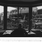 "50 3165 auf einer Drehscheibe in einem Bw. DEZEMBER. Kalender zeigt den Monat mit hervorgehobenem Datum. Person am Schreibtisch."