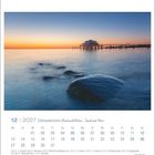 Kalenderblatt Dezember 2027: Ostseeküste, Wind und Wellen. Foto: Wellen, Steine, Steg bei Sonnenuntergang.