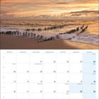 Kalenderseite mit Dezember 2027. Text: "SYLT... wie ich es liebe!" Himmel in warmen Tönen, Strand mit Holzpfählen im Wasser.