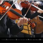 Kalenderblatt mit Monatsnummer 12 und hervorgehobenen Wochenzahlen 5, 12, 19, 26. Musiker mit Geige im Anzug.