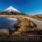 Kalender mit Mt. Taranaki, 2.518m. Ein Holzweg führt an einem See entlang, der Berg hat eine schneebedeckte Spitze.