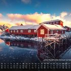 Rote Fischerhütten (Rorbuer) auf den Lofoten 12. Schneebedeckte Hütten am Wasser, bergige Landschaft im Hintergrund.