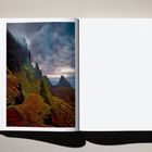 Seite 79. Links ein Foto von dramatischen Bergen unter bewölktem Himmel, rechts eine leere Seite.