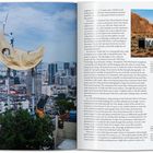 Texte auf der rechten Seite beschreiben Projekte von JR. Links steht eine Figur auf einem großen Mond über einer Stadt.