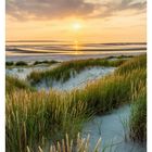 12. März, Sanddünen mit Gras bei Sonnenuntergang, orange und rosa Himmel, reflektiertes Licht im Wasser.