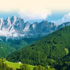 Text "LAND UND LEUTE"; malerische Landschaft mit grünen Hügeln, verstreuten Häusern und imposanten grauen Berggipfeln.