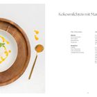 "Kokosmilchreis mit Mangopüree. Milchreis: 250 ml Kokosmilch, 250 ml Milch, 100 g Milchreis, 50 g Zucker. Mangopüree: 1 Mango, ½ EL Puderzucker, ½ EL Limettensaft, 1 Stängel Zitronenmelisse. Darstellung eines angerichteten Desserts auf einem Holzbrett."