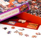 Puzzle-Box mit Aufschrift "DER TOD AUF DEM NIL". Obenauf liegen bunte Puzzleteile.