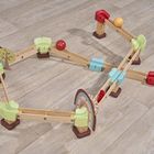 Holzspielzeugstrecke mit bunten Kugeln auf hellem Holzfußboden, farbige Abschnitte, Bäume und Häuser als Dekoration.
