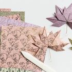 Gefaltete Papierblätter vor farbig gemusterten Papierschichten; liegt auf weißer Oberfläche mit Falzbein.
