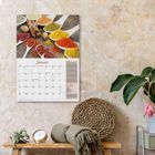 "Januar" in roter Schrift auf einem Kalender. Oben diverse Gewürze, unten Pflanzen und Deko auf einem Holztisch.